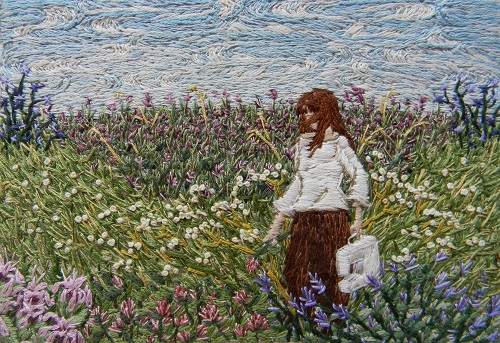 An embroidered panel of a woman in a field of flowers, carrying a sewing machine;