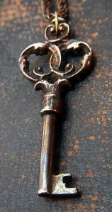 An elaborate old metal key on a rusty chain