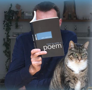 Brian Bilston publicity photo. His face completely covered by the book he is reading (How to Write a Poem), while a cat sits in the foreground, gazing into the camera. And his middle finger supports the spine of the book in a protrusive way, but I'm sure that's an accident